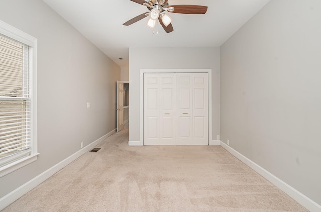 unfurnished bedroom with visible vents, baseboards, ceiling fan, a closet, and light carpet