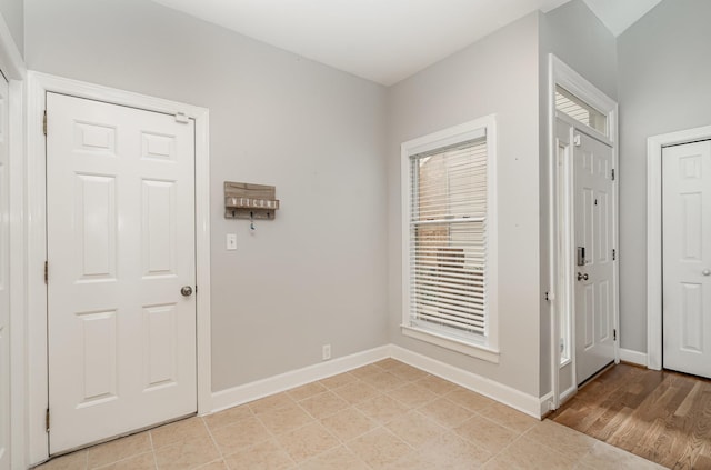 foyer entrance with light tile patterned flooring and baseboards