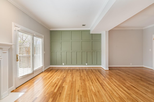 unfurnished room featuring baseboards, visible vents, light wood-style flooring, ornamental molding, and a decorative wall