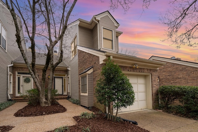 view of front of house featuring concrete driveway, an attached garage, and brick siding