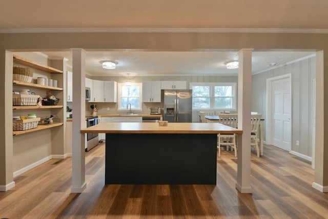 kitchen featuring white cabinetry, light countertops, wood finished floors, and appliances with stainless steel finishes