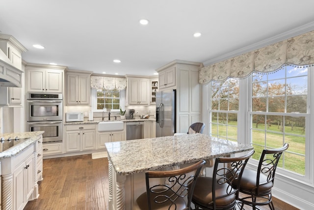 kitchen with a breakfast bar, stainless steel appliances, light stone counters, and a sink