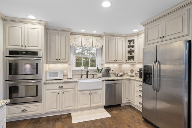 kitchen with dark wood-style floors, backsplash, stainless steel appliances, and a sink