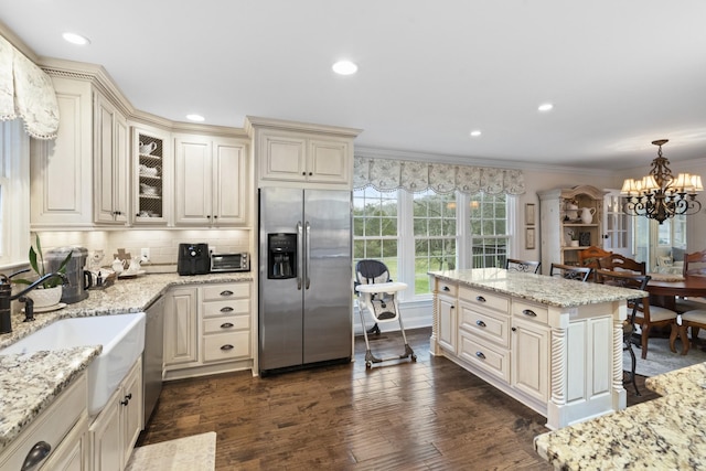 kitchen with dark wood finished floors, cream cabinets, stainless steel appliances, and a sink