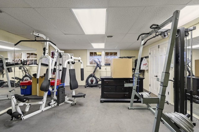 gym with a drop ceiling and concrete block wall