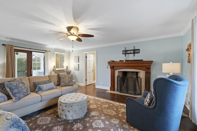 living area with wood finished floors, baseboards, a fireplace with flush hearth, ceiling fan, and crown molding