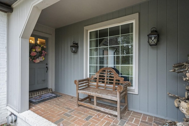 doorway to property featuring brick siding and a porch