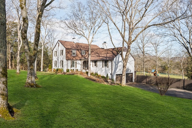 view of yard featuring aphalt driveway, a garage, and fence