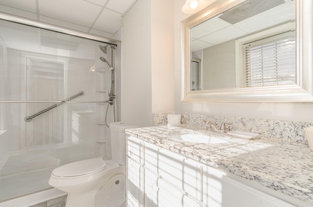 bathroom with a paneled ceiling, toilet, a stall shower, and vanity