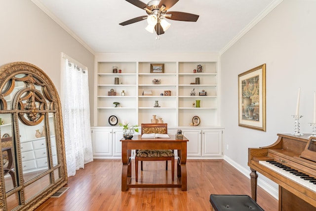 home office with baseboards, visible vents, light wood finished floors, ceiling fan, and ornamental molding