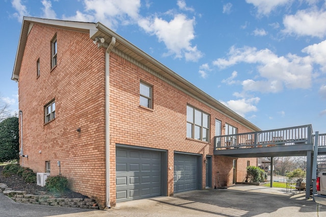 view of side of property with a garage, brick siding, and driveway