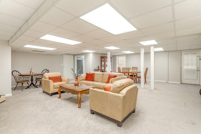 living area featuring a paneled ceiling, baseboards, and light carpet