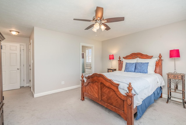 bedroom with a ceiling fan, ensuite bath, light colored carpet, and baseboards