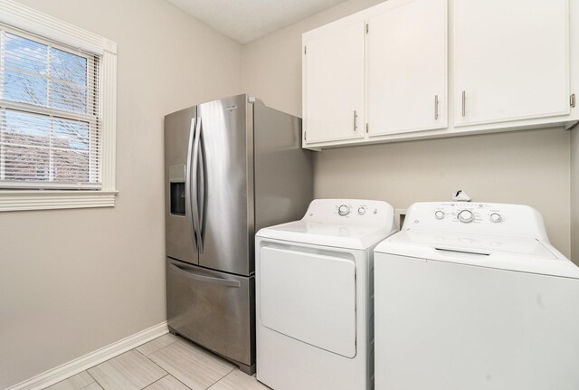 laundry area with baseboards, cabinet space, and washer and clothes dryer