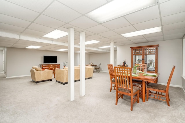 dining room with a drop ceiling, light colored carpet, and baseboards