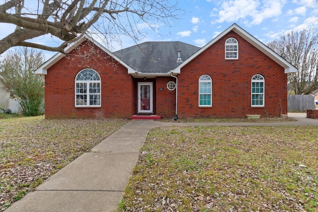 view of front facade with brick siding, roof with shingles, and a front yard