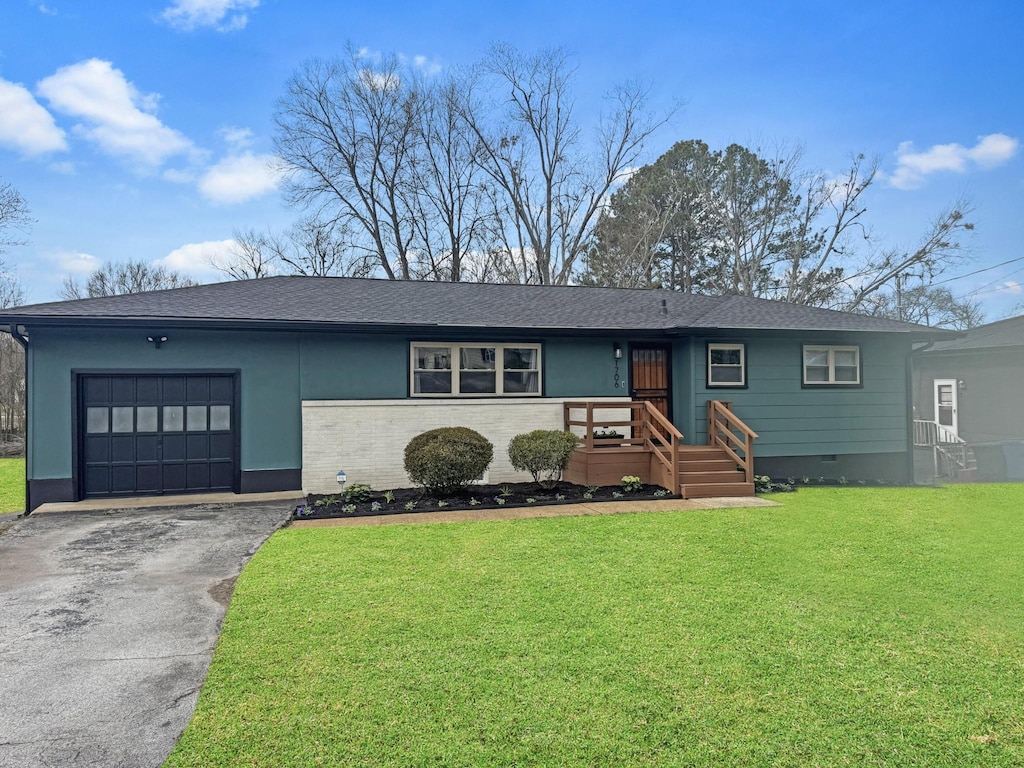 view of front of house with aphalt driveway, an attached garage, a shingled roof, and a front lawn