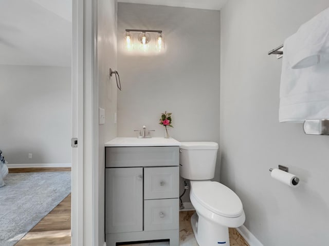 bathroom with toilet, vanity, and baseboards