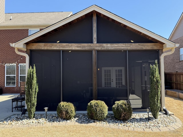 exterior space featuring fence, french doors, brick siding, and a sunroom