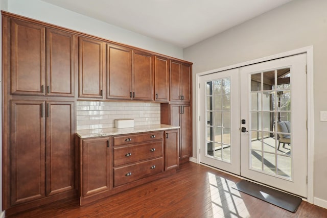 kitchen with tasteful backsplash, baseboards, light stone countertops, french doors, and dark wood-style floors