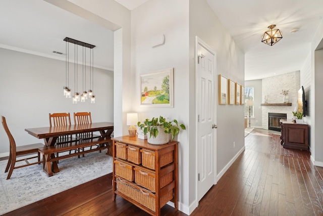 corridor with dark wood-type flooring, a notable chandelier, visible vents, and baseboards