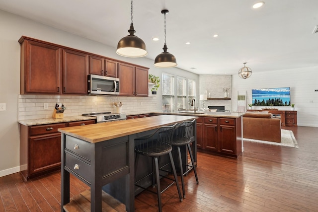 kitchen with a peninsula, butcher block countertops, stove, dark wood-type flooring, and stainless steel microwave