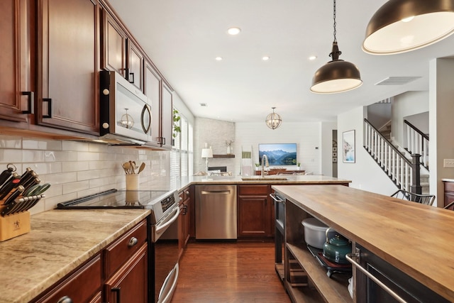 kitchen with dark wood-style floors, wooden counters, stainless steel appliances, decorative backsplash, and pendant lighting