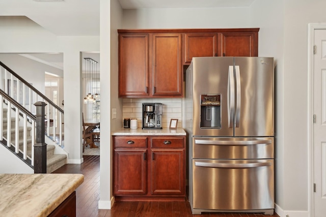 kitchen with dark wood-type flooring, baseboards, stainless steel fridge with ice dispenser, decorative backsplash, and light stone countertops