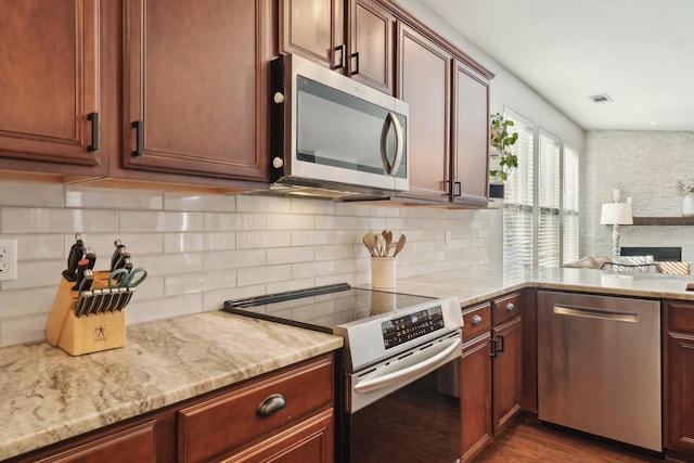 kitchen with visible vents, backsplash, light stone counters, dark wood-style floors, and stainless steel appliances