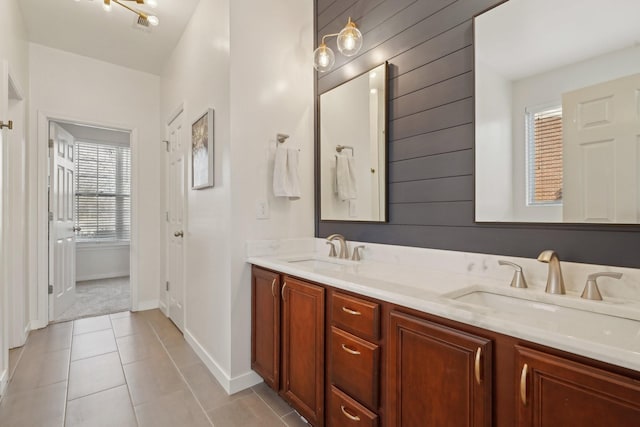 full bath featuring a sink, baseboards, double vanity, and tile patterned floors