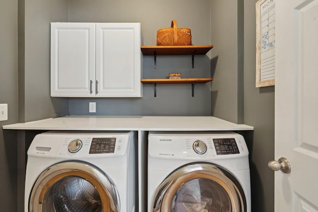 clothes washing area featuring cabinet space and washing machine and clothes dryer