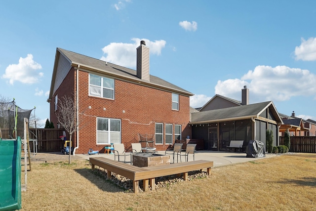 back of property with a yard, a sunroom, a trampoline, and fence