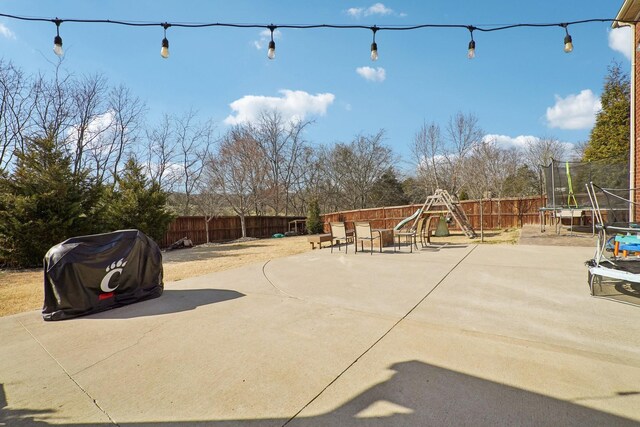 view of patio with a fenced backyard, a playground, and a trampoline