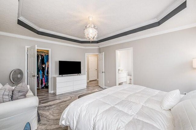 bedroom with a spacious closet, a notable chandelier, a raised ceiling, and a closet