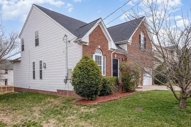 view of side of property featuring brick siding, an attached garage, a shingled roof, and a yard