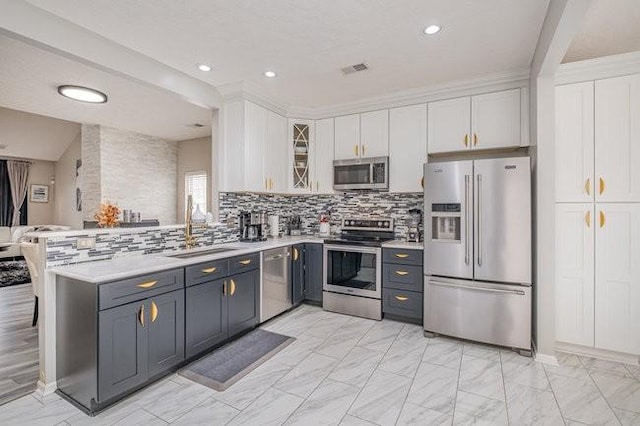 kitchen featuring stainless steel appliances, a peninsula, white cabinets, and light countertops