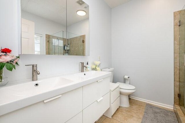 bathroom with visible vents, toilet, a shower stall, double vanity, and baseboards