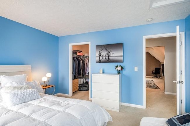 bedroom with a walk in closet, carpet flooring, baseboards, and a closet