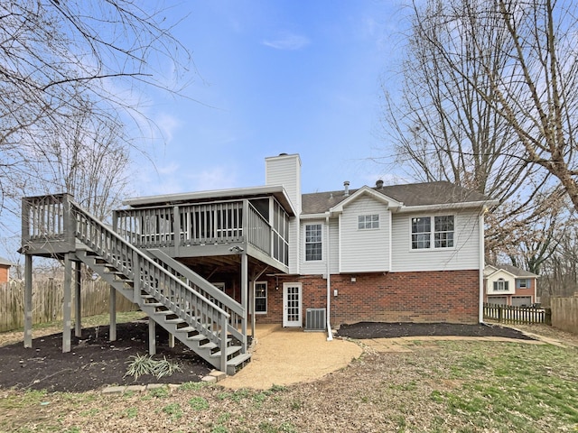 rear view of property with brick siding, fence, stairs, a chimney, and a deck