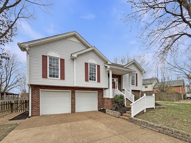 bi-level home with brick siding, concrete driveway, a garage, and fence