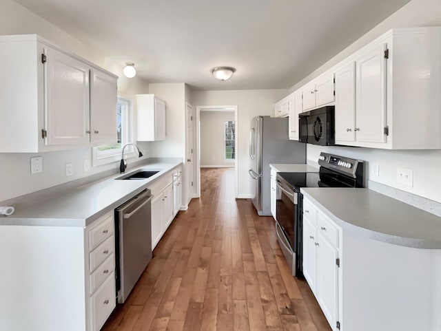 kitchen featuring light wood-style flooring, white cabinetry, stainless steel appliances, and a sink