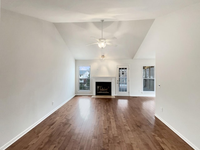 unfurnished living room with dark wood finished floors, a fireplace with flush hearth, baseboards, and ceiling fan