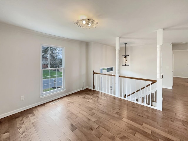 unfurnished room with a wealth of natural light, visible vents, and wood finished floors