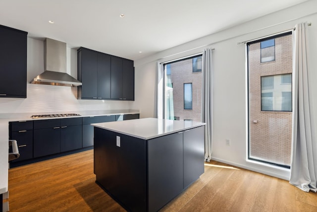 kitchen featuring light countertops, wall chimney exhaust hood, light wood-style floors, and stainless steel gas cooktop