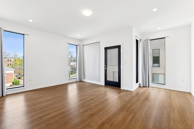 unfurnished room with plenty of natural light, wood finished floors, and recessed lighting