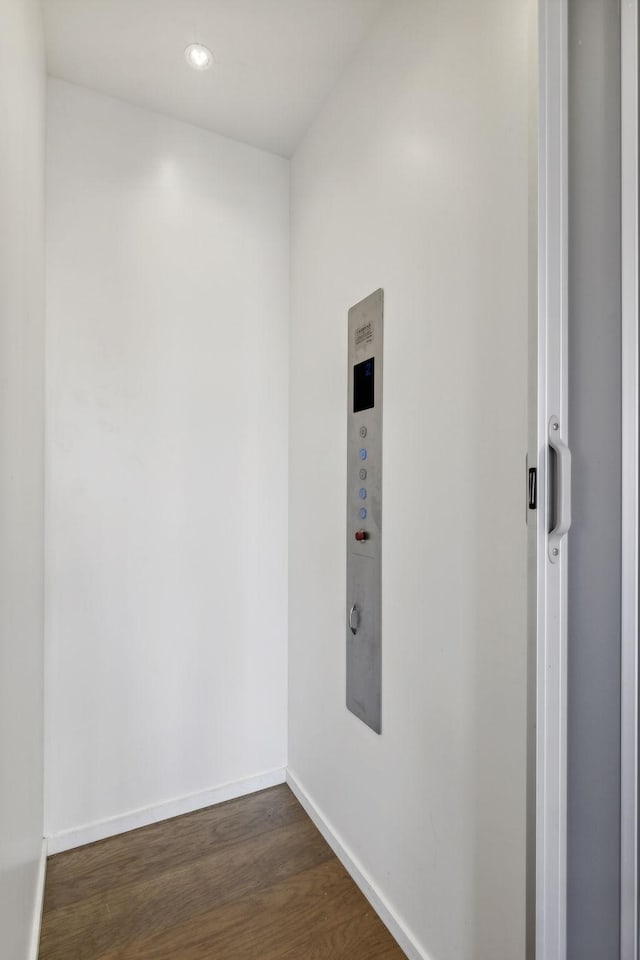 unfurnished room featuring baseboards and dark wood-type flooring