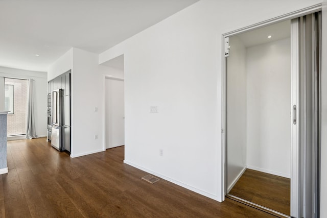 interior space featuring dark wood-style floors, visible vents, baseboards, and elevator