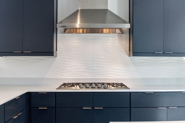 kitchen with modern cabinets, blue cabinetry, wall chimney range hood, stainless steel gas stovetop, and light countertops