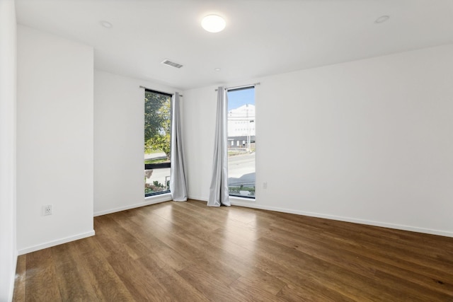 empty room featuring visible vents, baseboards, and wood finished floors