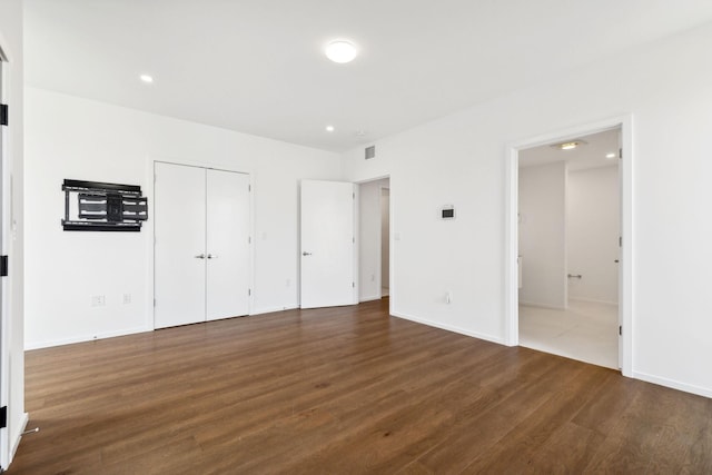 unfurnished bedroom with visible vents, wood finished floors, recessed lighting, connected bathroom, and baseboards